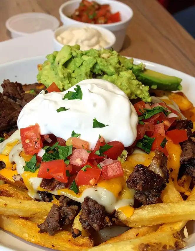 French Fries with steak, melting cheese, sour cream, and diced tomatoes