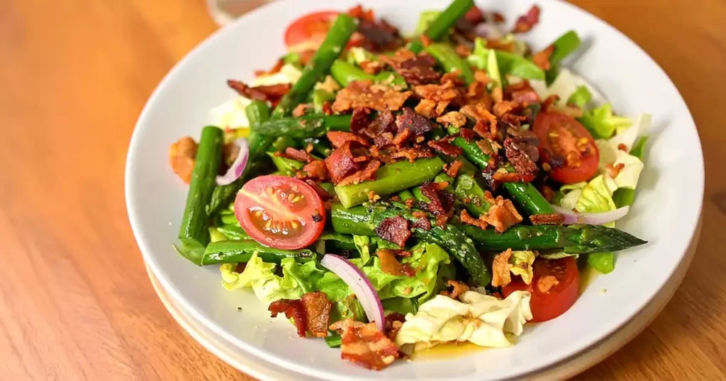 A plate of asparagus salad with bacon