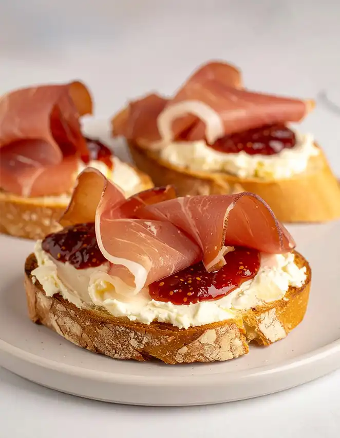 A plate of Prosciutto Crostini with fig jam
