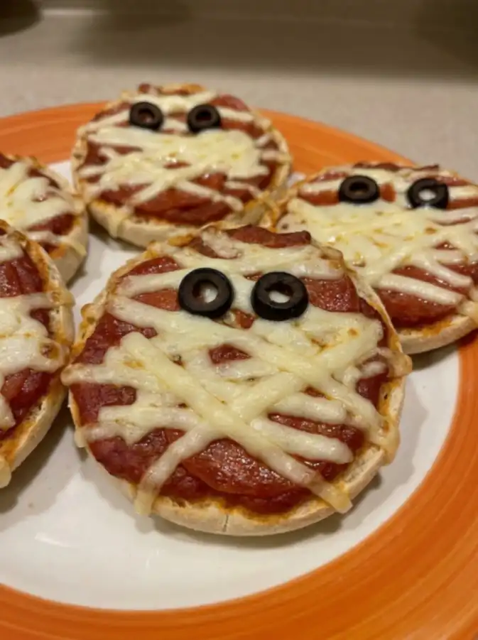 Mummy Halloween pizza with shredded cheese and olive