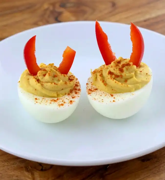 Halloween deviled eggs with red bell pepper strips as horns